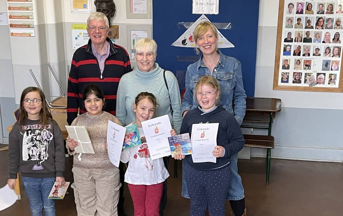 Kinder stehen mit Lehrkräften und ihren Urkunden lachend da.